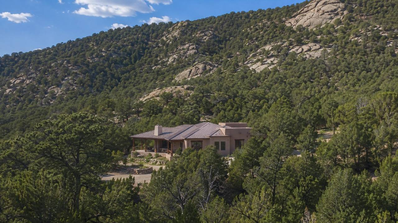 Home nestled among dense piñon and juniper forest in the East Mountains near Albuquerque, with granite rock outcroppings